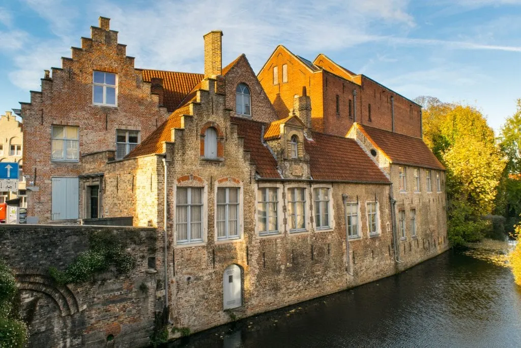 brick buildings along a small canal in bruges. canals are a popular reason to visit both ghent and bruges
