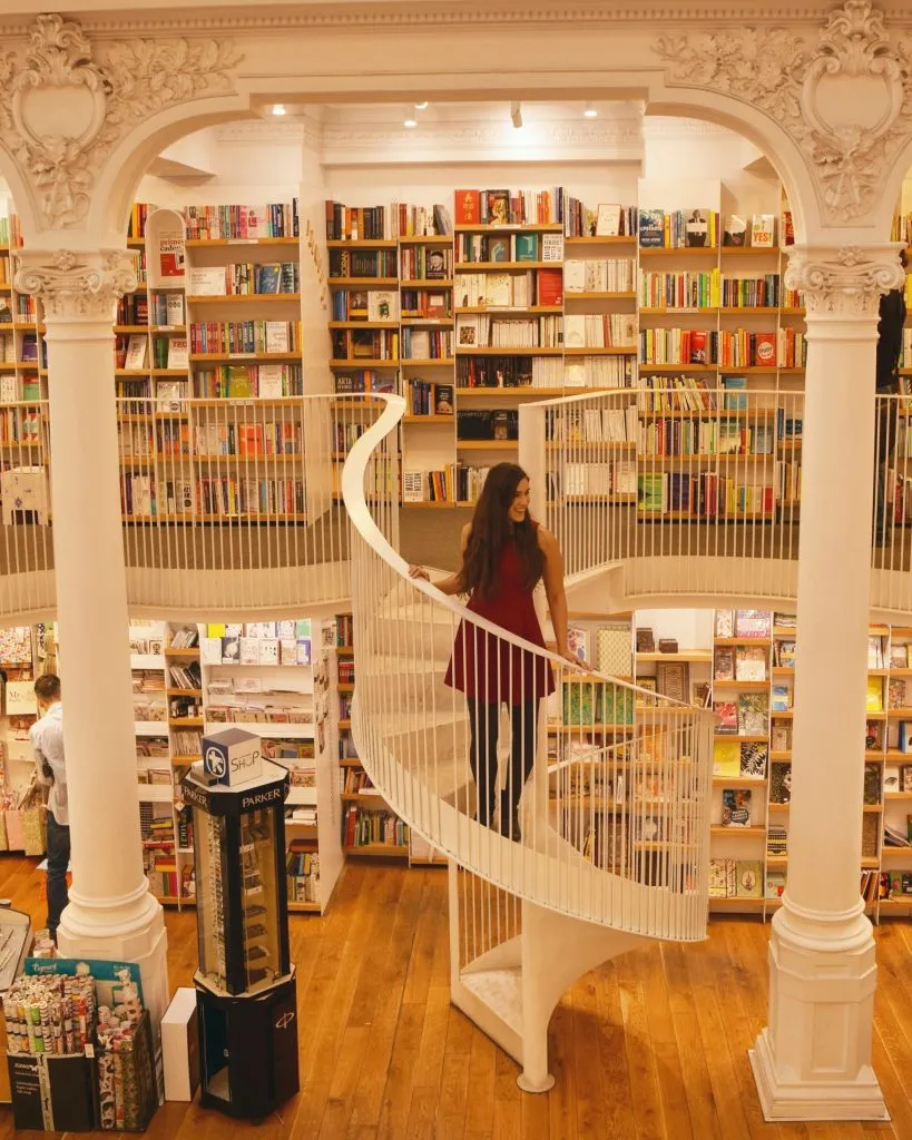 kate storm in a red dress on a staircase in a bookstore in bucharest romania