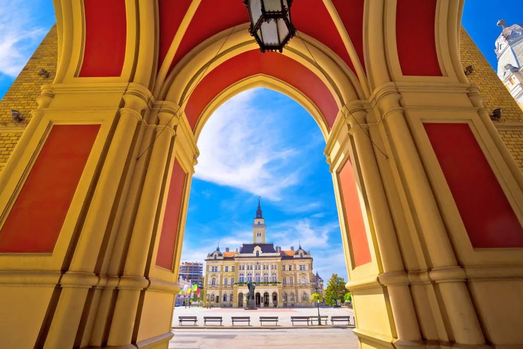 view of freedom square in novi sad serbia as seen through colorful red and yellow arches novi sad is one of the cheapest european cities to visit