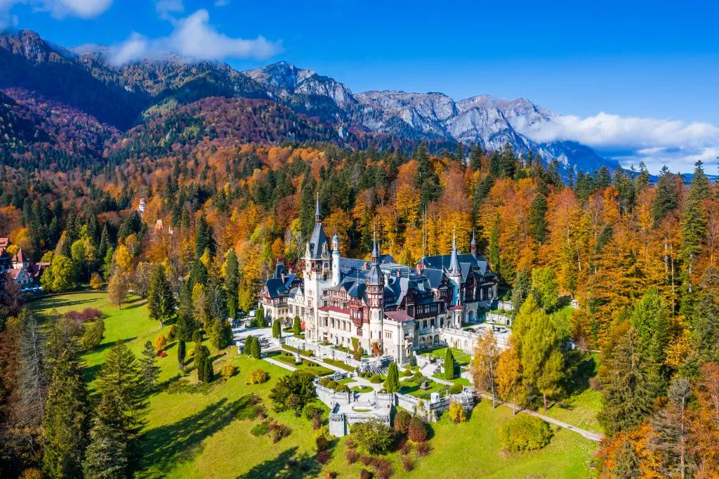 aerial view of peles castle romania with fall foliage surrounding it