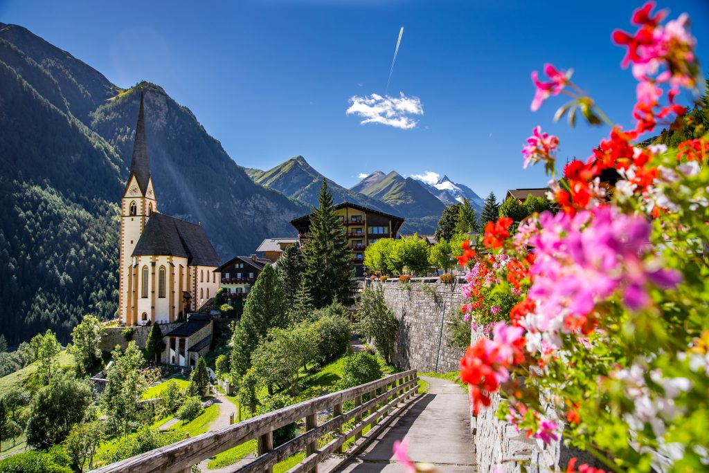 st vincent church with pink flowers blooming to the right Heiligenblut, Austria, one of the best offbeat places in europe