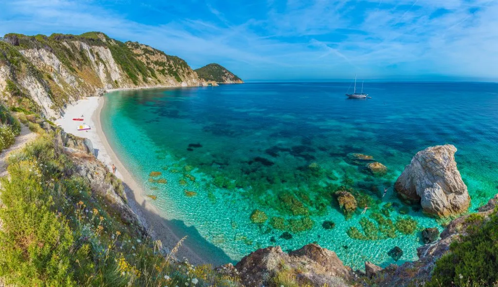 bright turquoise beach with land visible to the left on elba island, one of the best places to visit in tuscany italy