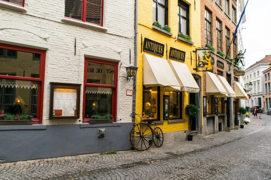 antique store painted yellow on a curving street in bruges--views like this are common in either ghent or bruges