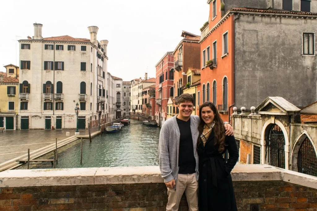 kate storm and jeremy storm in front of a canal in venice in winter, one of the best things to see in italy