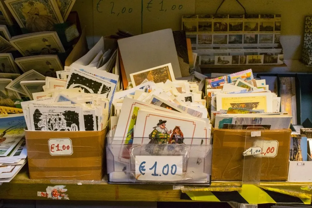 Pile of postcards for sale at Libreria Acqua Alta Venice. Bins are marked with 1 Euro price tag.