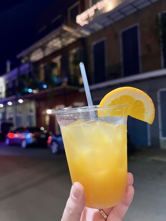 hurricane cocktail being held up in the french quarter nola on a ghost tour at night
