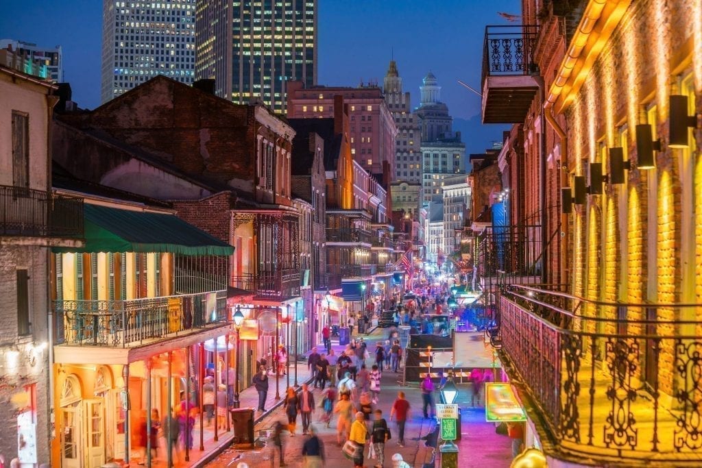 Street in NOLA French Quarter at night with neon lights from the bars lighting it up--don