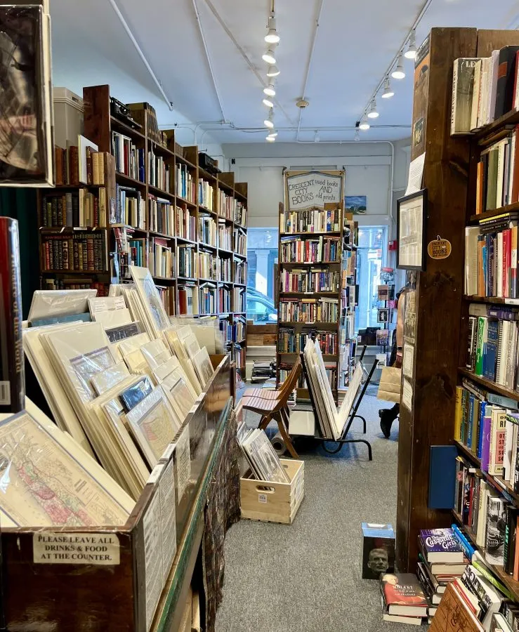 interior of crescent city books with stack of prints on the left and bookshelves on the right in new orleans