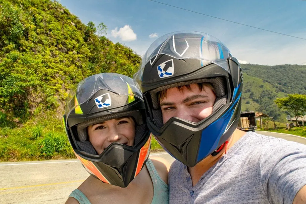 Kate Storm and Jeremy Storm wearing helmets and taking a selfie while exploring on a motorbike, one of the best things to do in Guatape Colombia