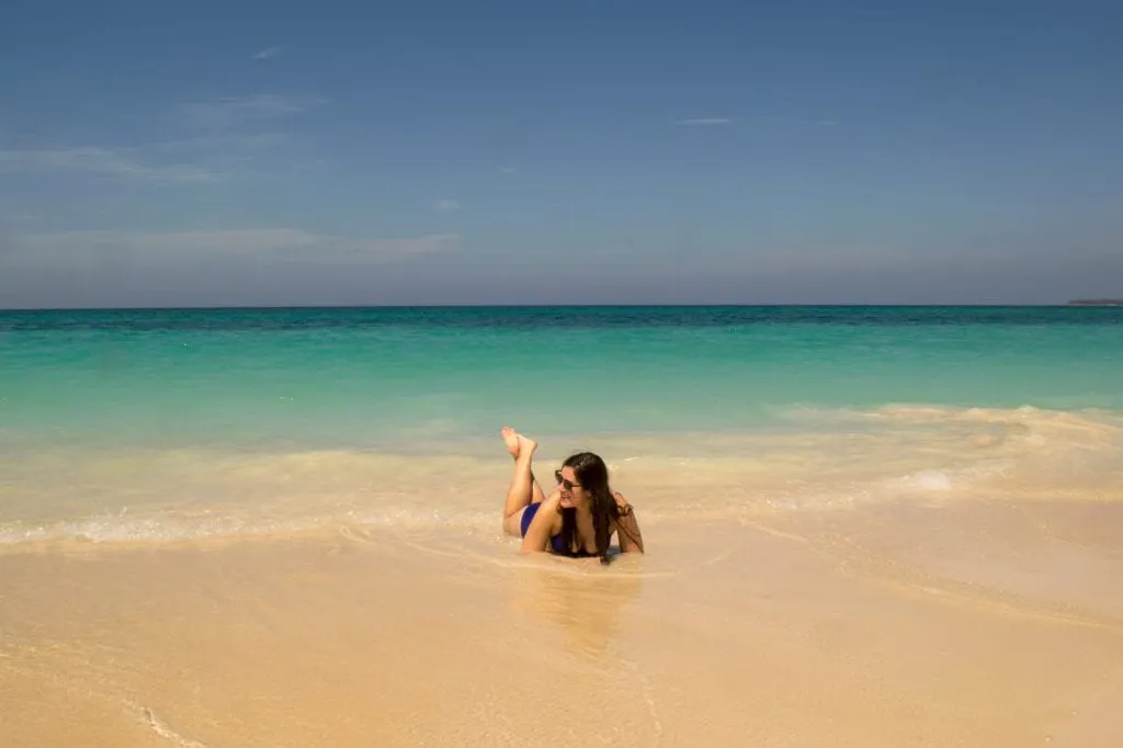 Kate Storm laying down on Playa Blanca with the sea surrounding her