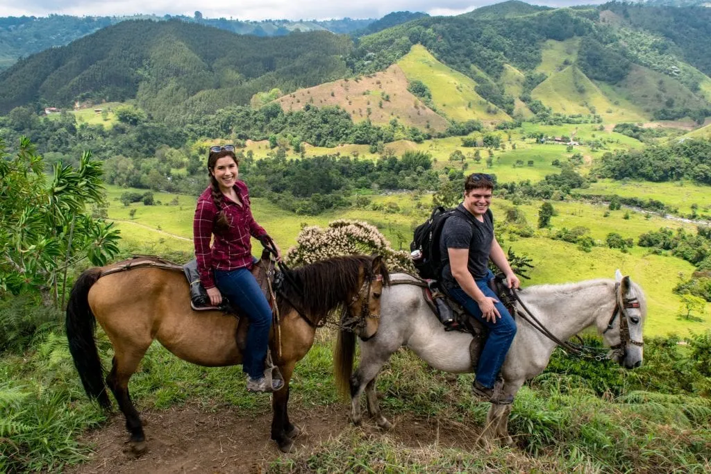 Kate Storm and Jeremy Storm riding horses into a valley near Salento Colombia, one of the best things to do in Salento Colombia