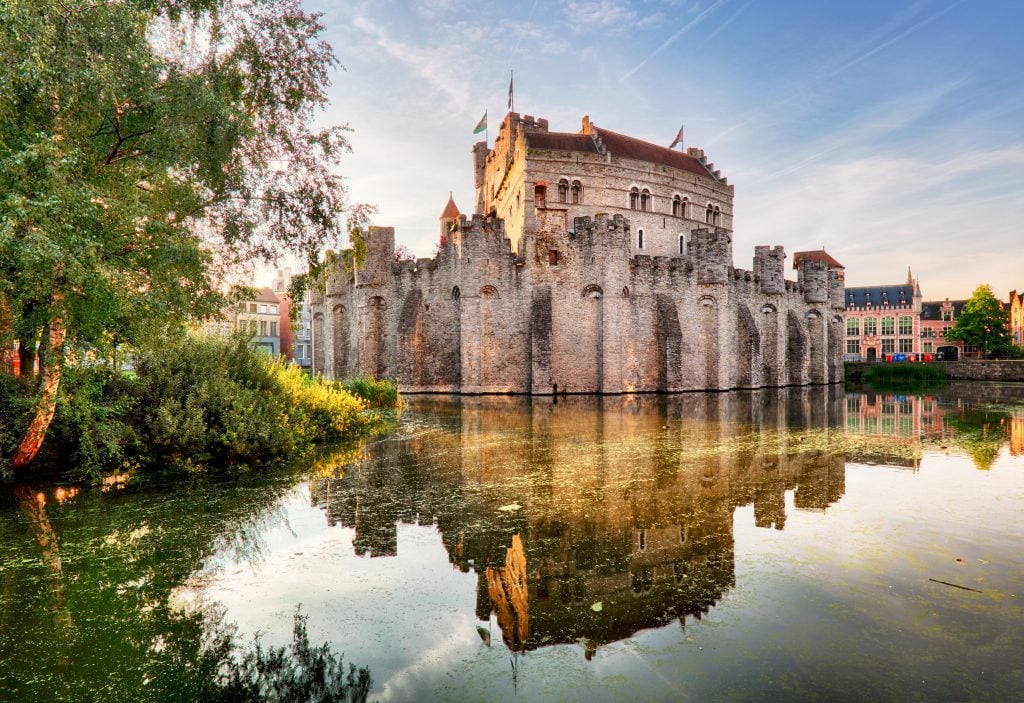 gravensteen castle near sunset as seen from across the canal, one of the best places to visit in ghent belgium