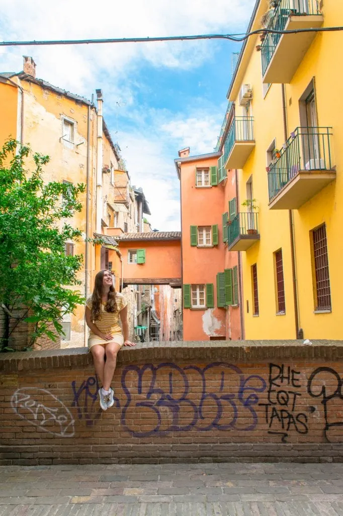 kate storm in a yellow dress sitting on a ledge in bologna italy emilia romagna itinerary 7 days