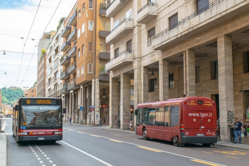 red buses driving along a street in bologna itinerary