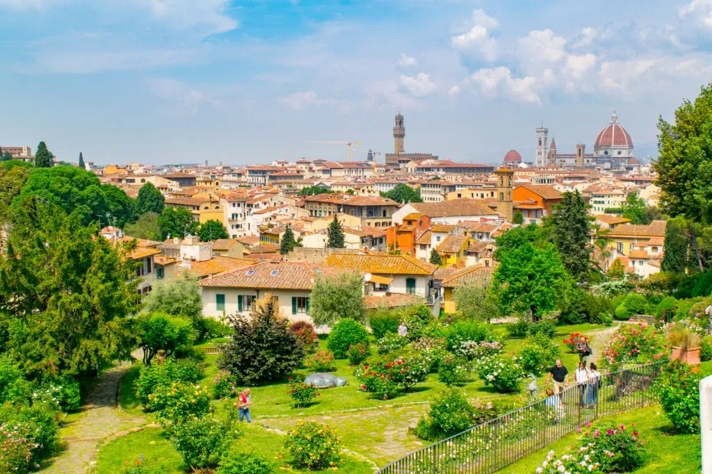 view of tourists visiting the blooming rose garden in florence with city skyline in the background