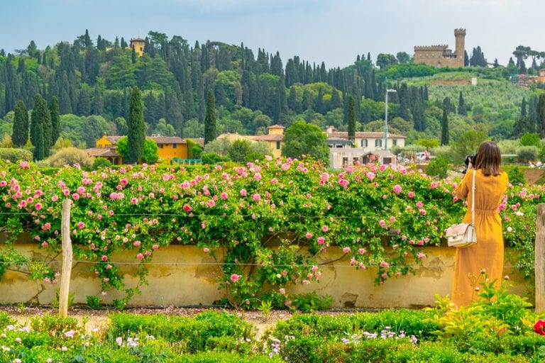 woman in a yellow dress taking pictures in boboli gardens, one of the most instagrammable photo spots in florence italy