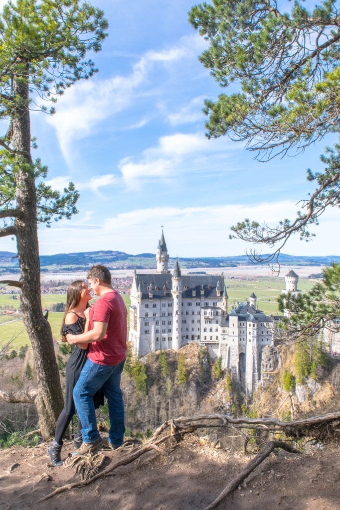 kate storm and jeremy storm in front of neushwanstein castle in germany, spring europe packing list