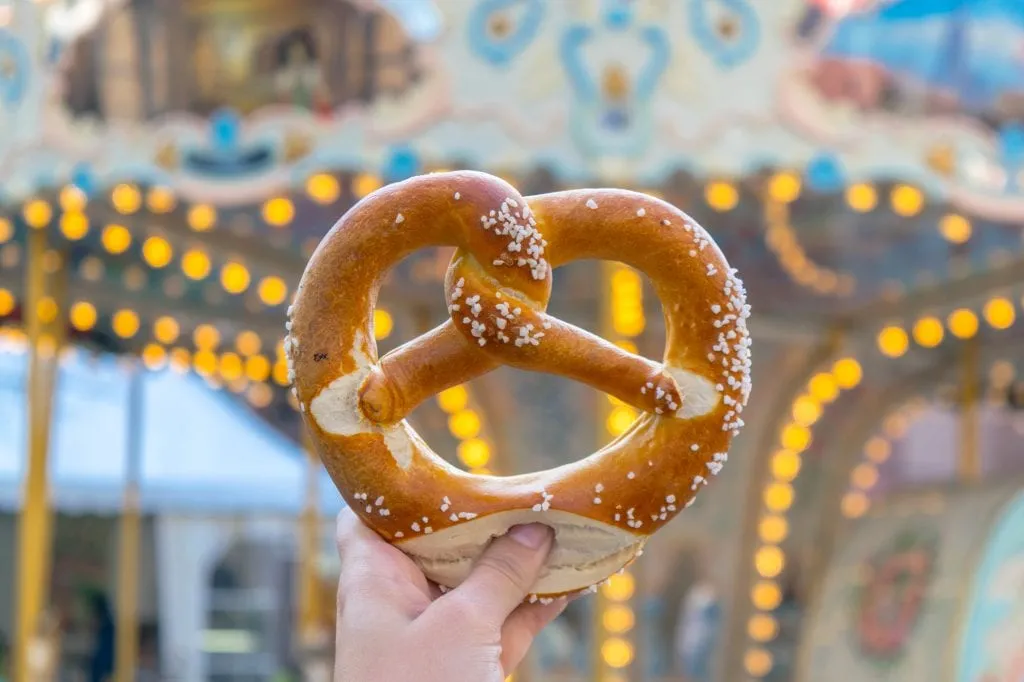 Pretzel being held up to a carousel in during one day in Strasbourg France