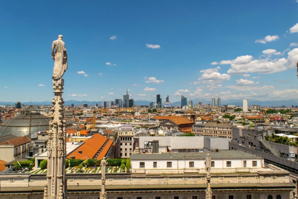 view of modern milan skyline with cathedral rooftop terrace spire in the foreground, one of the best things to do in piazza del duomo milan italy