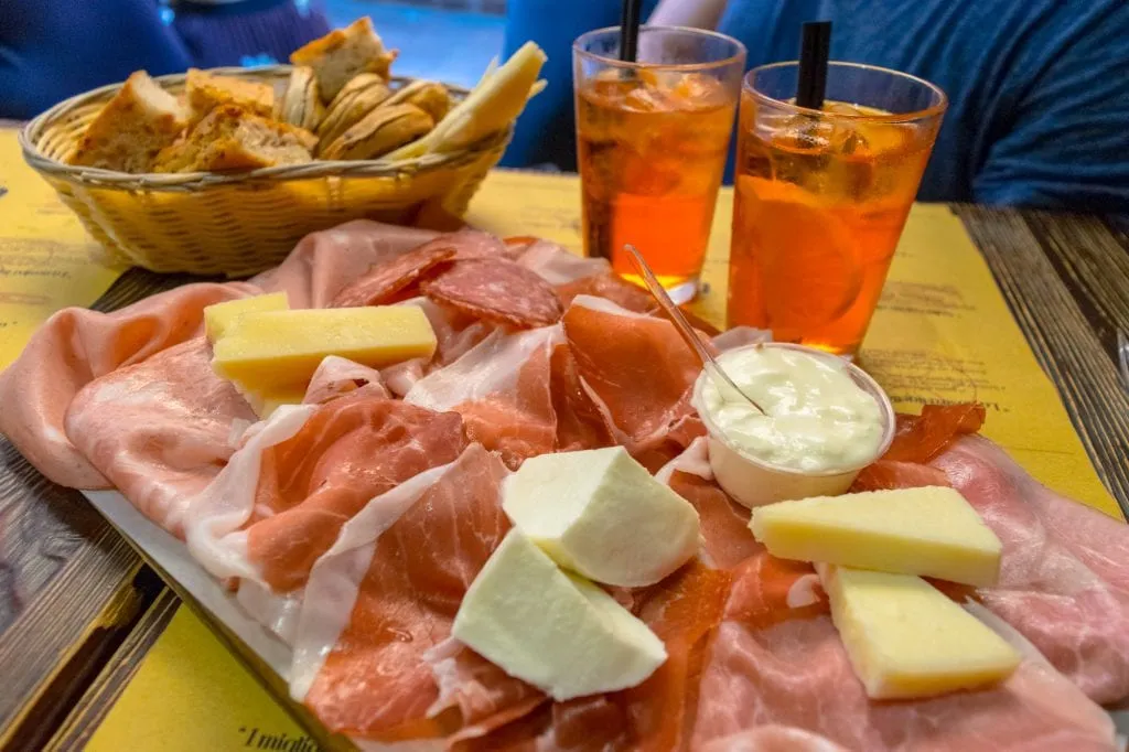 cured meats cheese and aperol sprizes on via drapperie in bologna italy