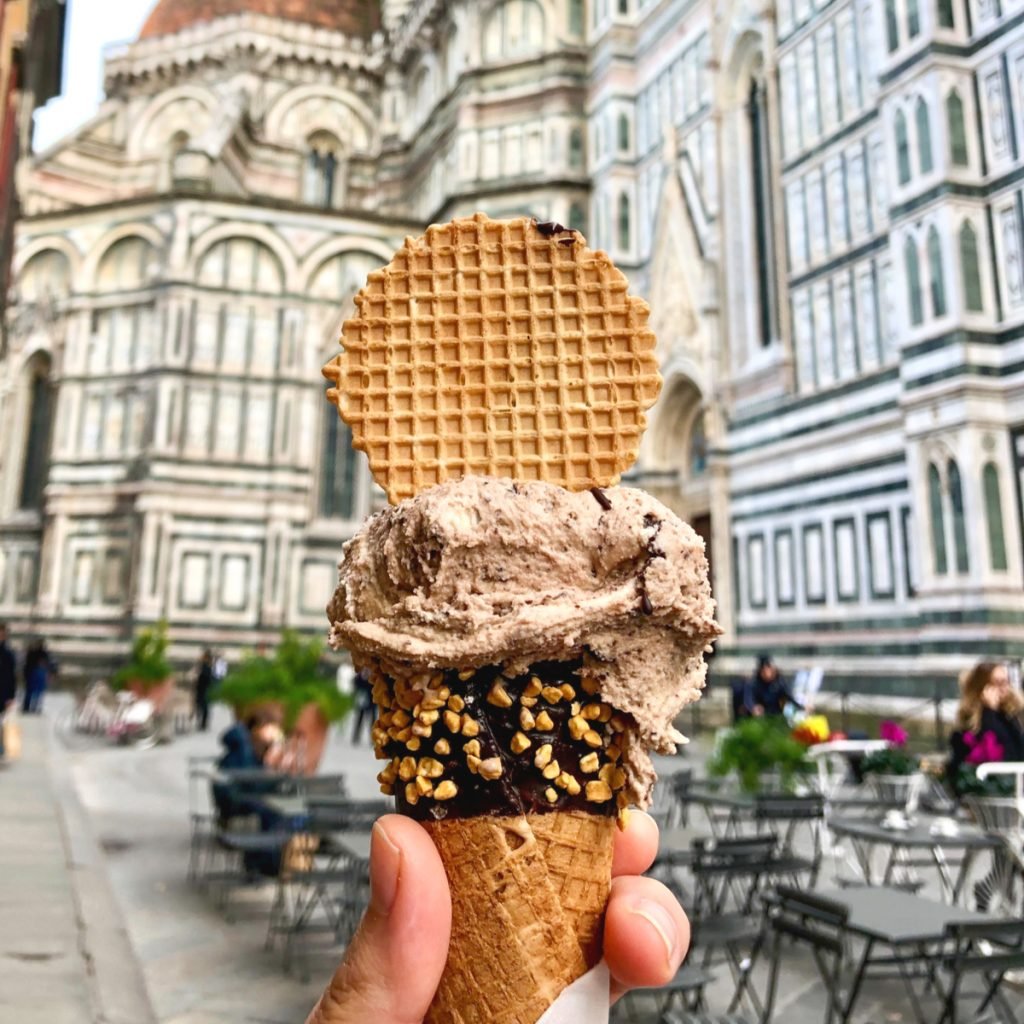 hand holding gelato out in front of duomo in florence italy