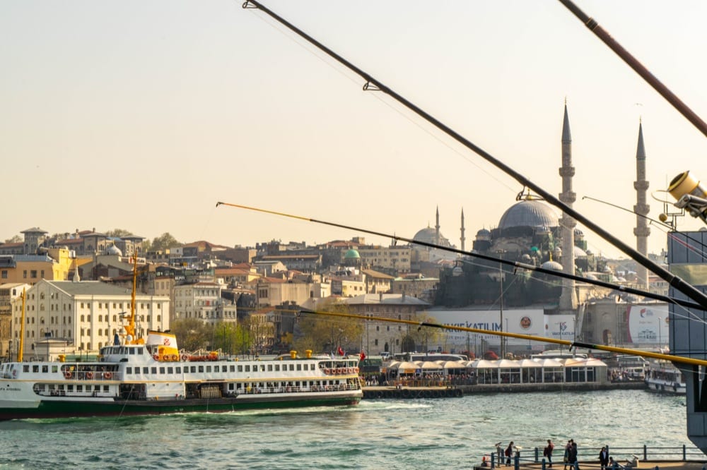 fishing poles over the galata bridge istanbul with a mosque visible in the background