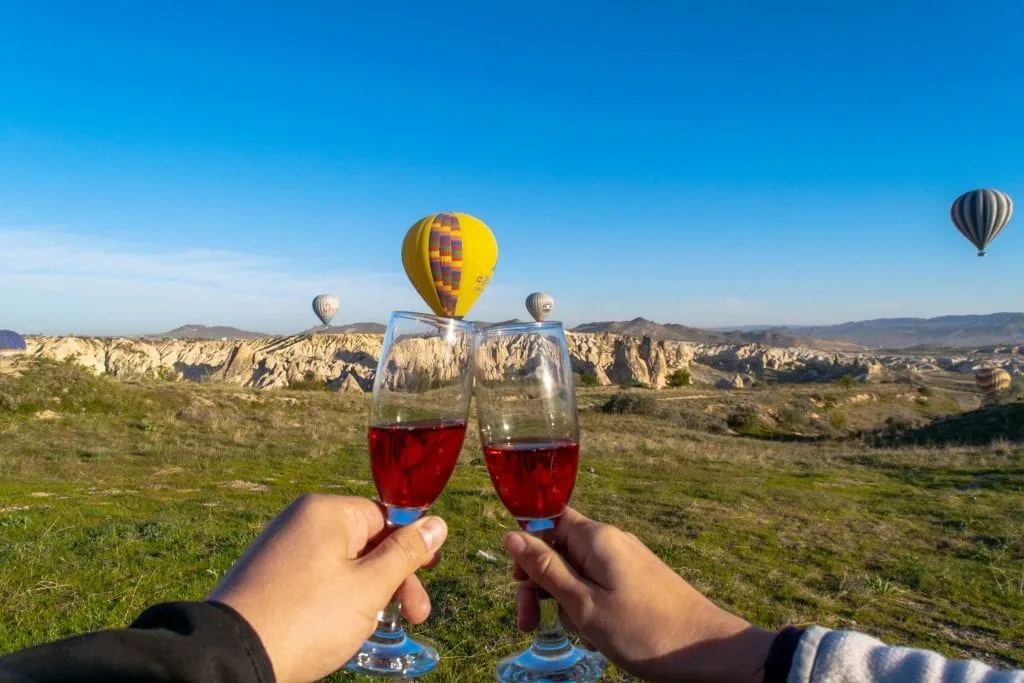 kate storm and jeremy storm toasting wine glasses in front of hot air balloons