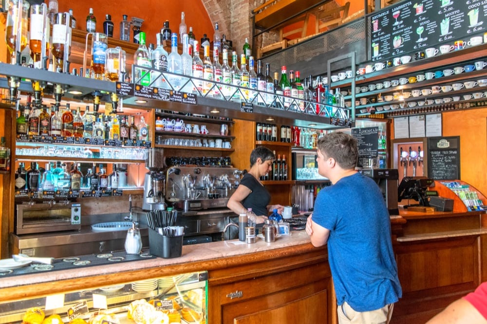 Jeremy standing in a bar in Siena, Italy. One of many important travel tips for Italy: an Italian bar serves both coffee and alcohol--you'll visit multiple times a day!