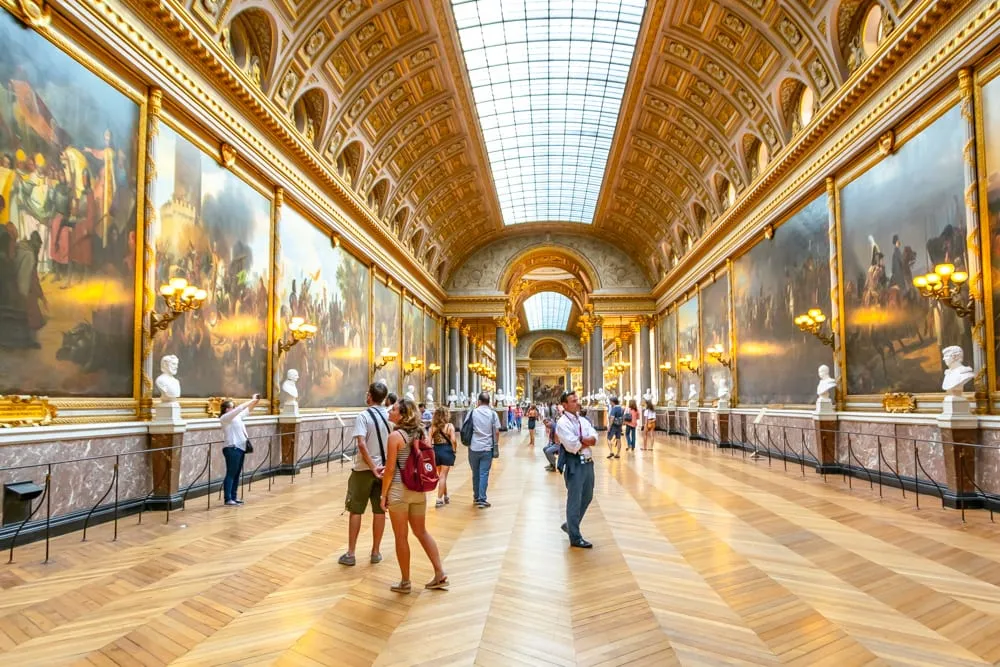 travelers admiring artwork inside versailles palace
