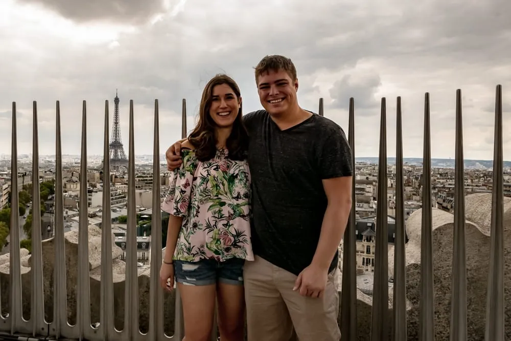 kate storm and jeremy storm visiting arc de triomphe paris with metal spikes in the background