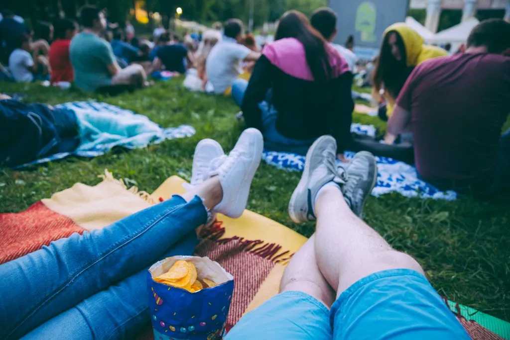 people on picnic blankets getting ready to watch a movie in a park