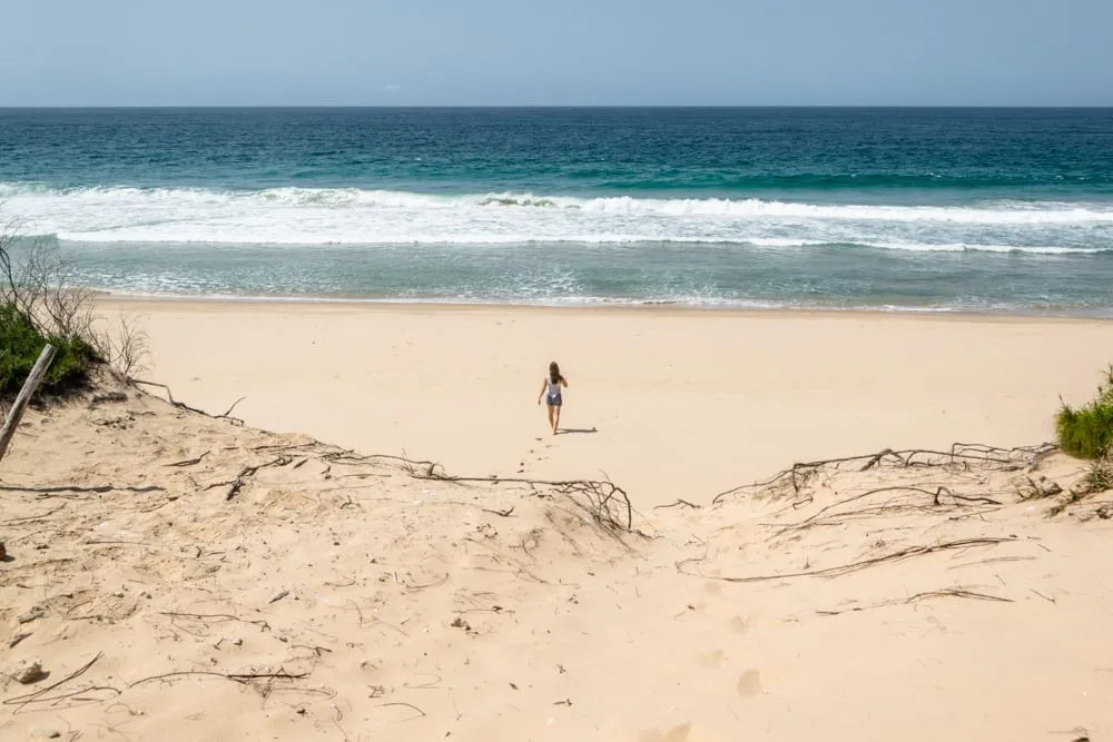 kate storm walking toward water on empty beach in tofo mozambique