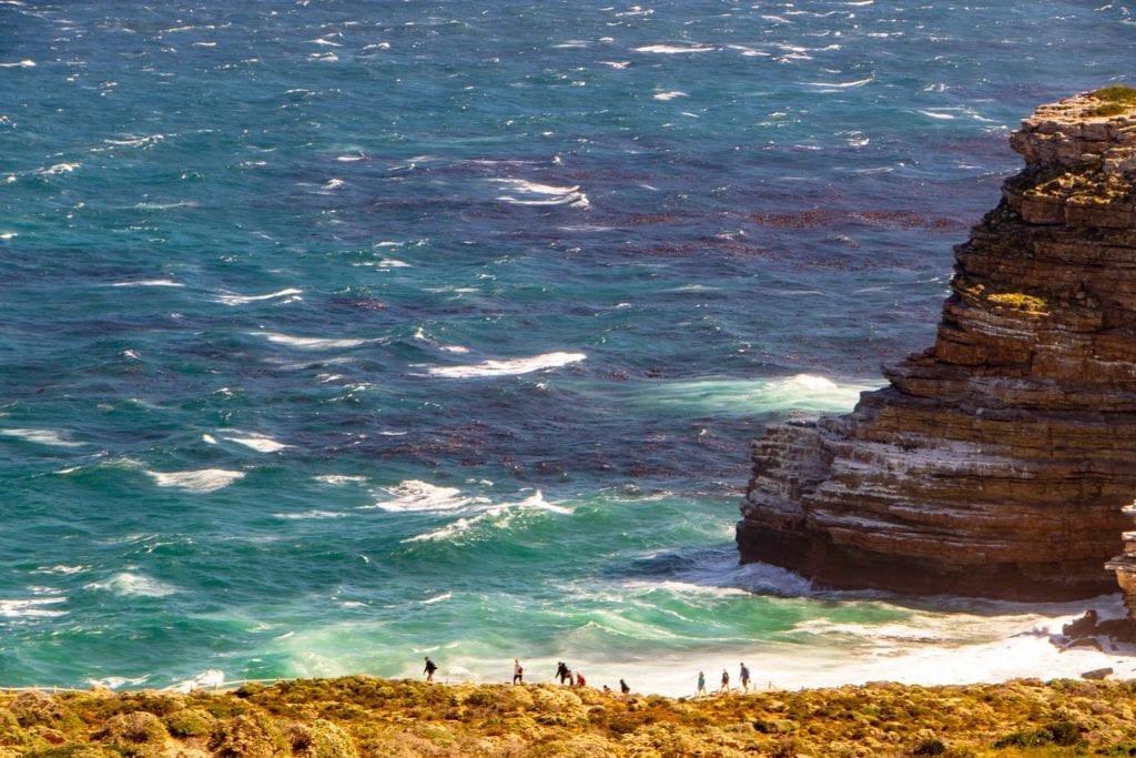 hikers along the edge of south africa with ocean in the backgroun. learning how to use airbnb can make experiences like this easier