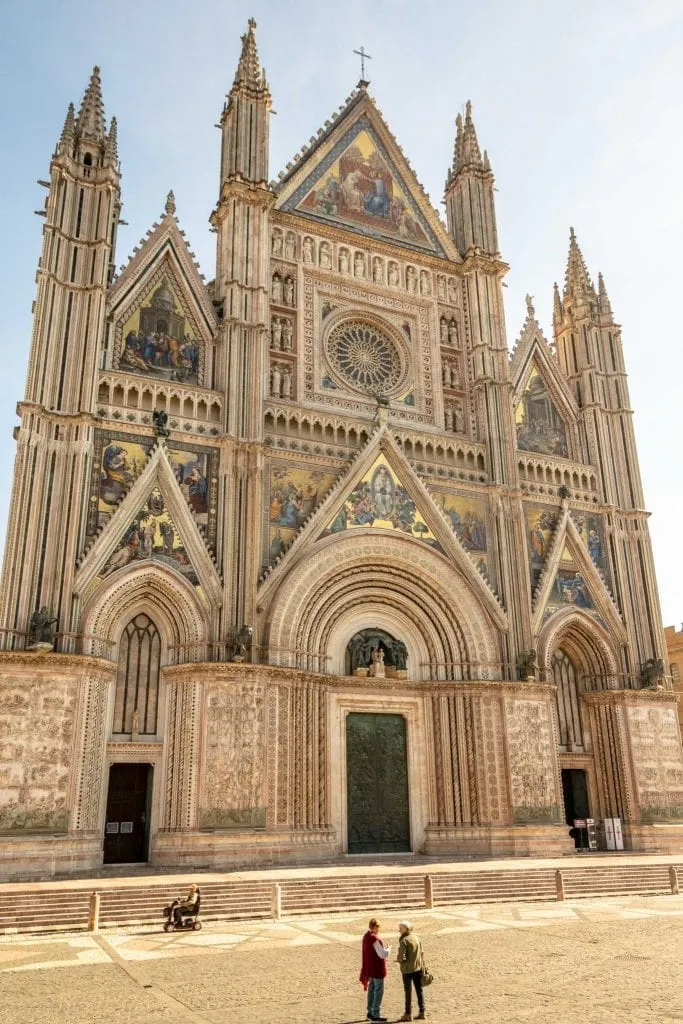 front facade of orvieto duomo with a few people in front of it