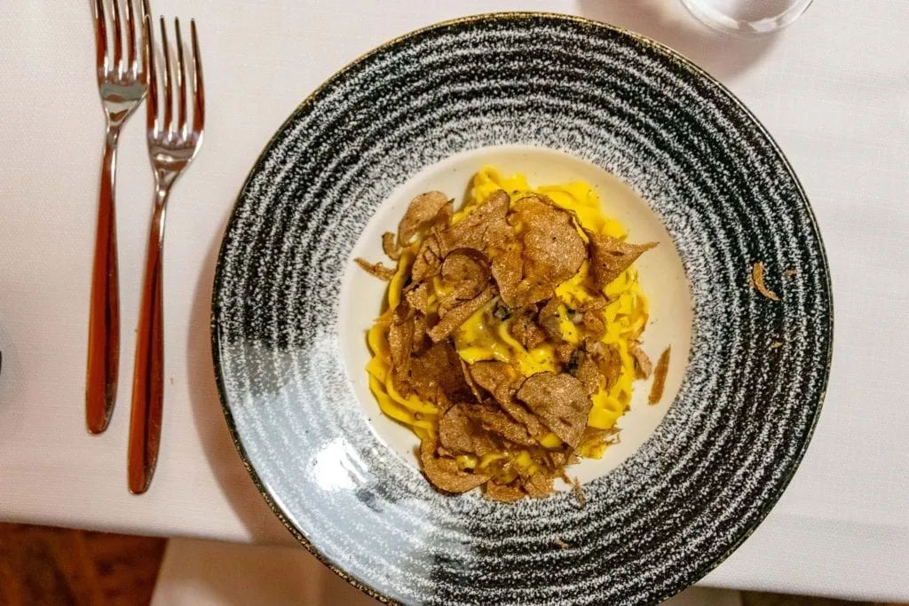 Pasta topped with truffles, shot from above in a black and white bowl. Truffles are one of the best things to eat in Florence Italy