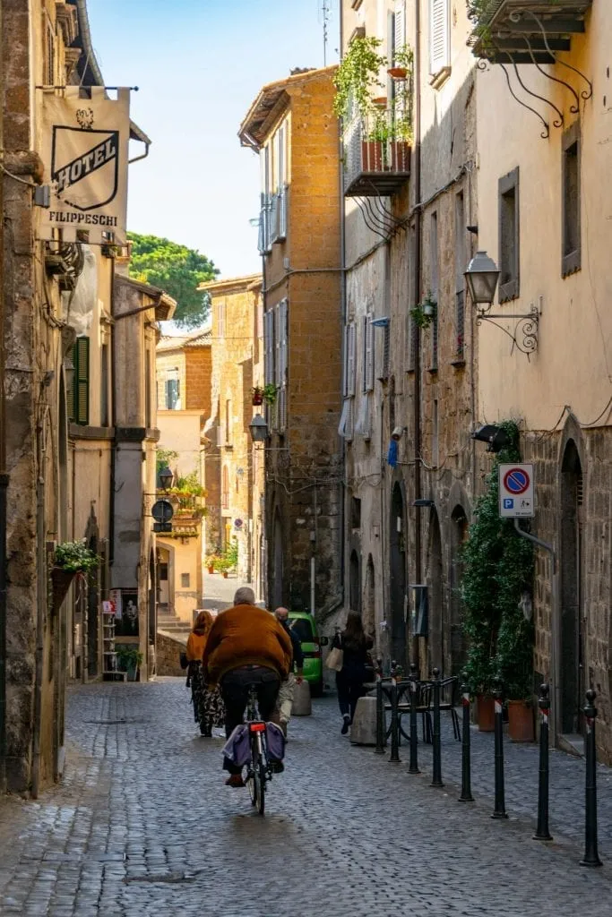 man riding a bike down a cobblestone street in orvieto italy