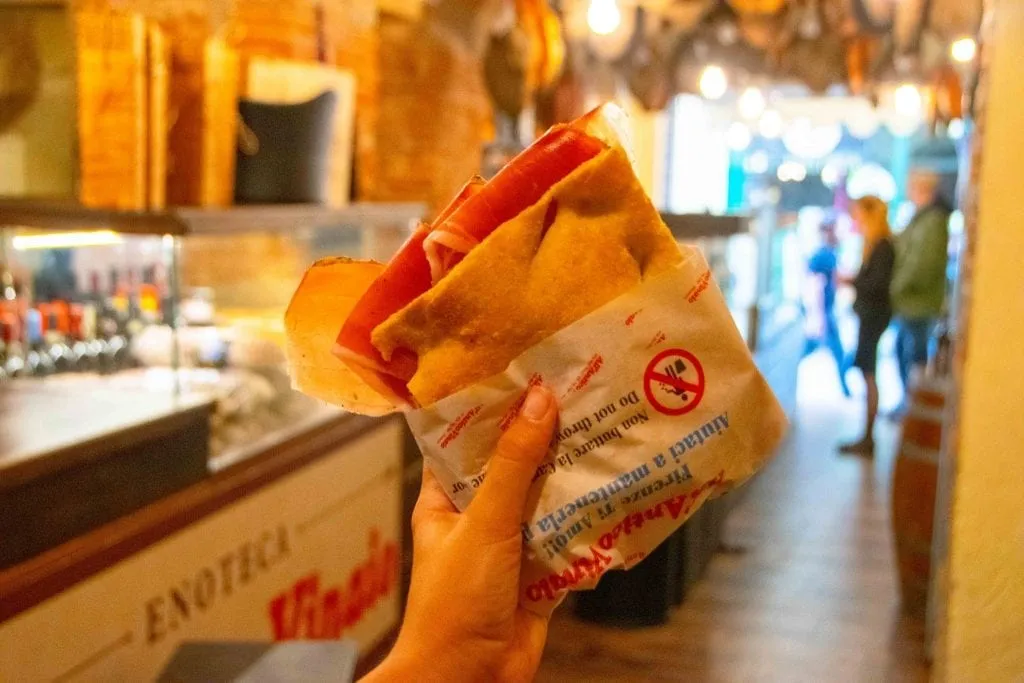 Panino being held up in front of a panino shop, one of the best places for lunch in Florence Italy