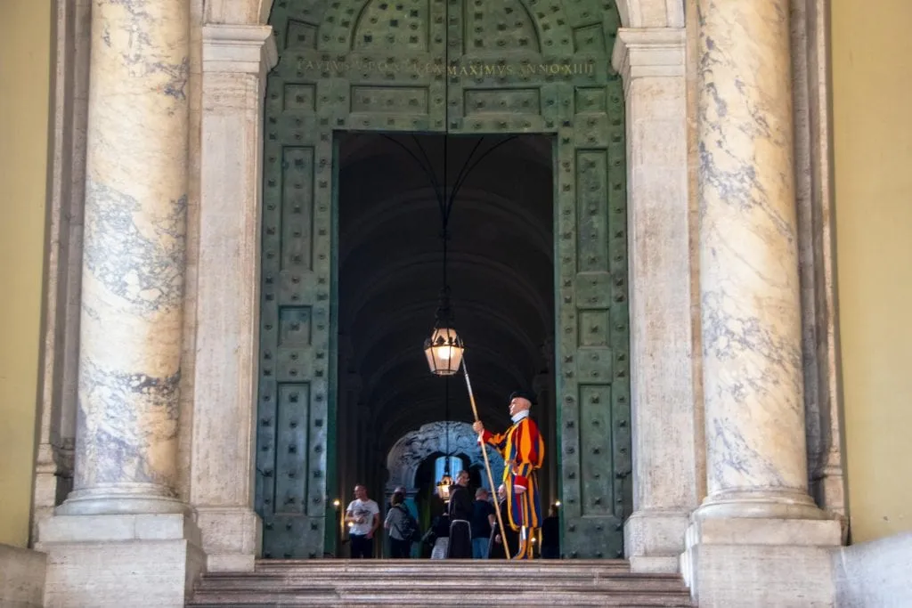 Vatican Guard standing in front of a large green door in Vatican City