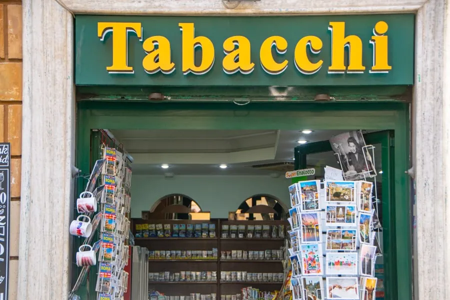 front door of a tabacchi in rome, green door with yellow lettering and postcards for sale out front
