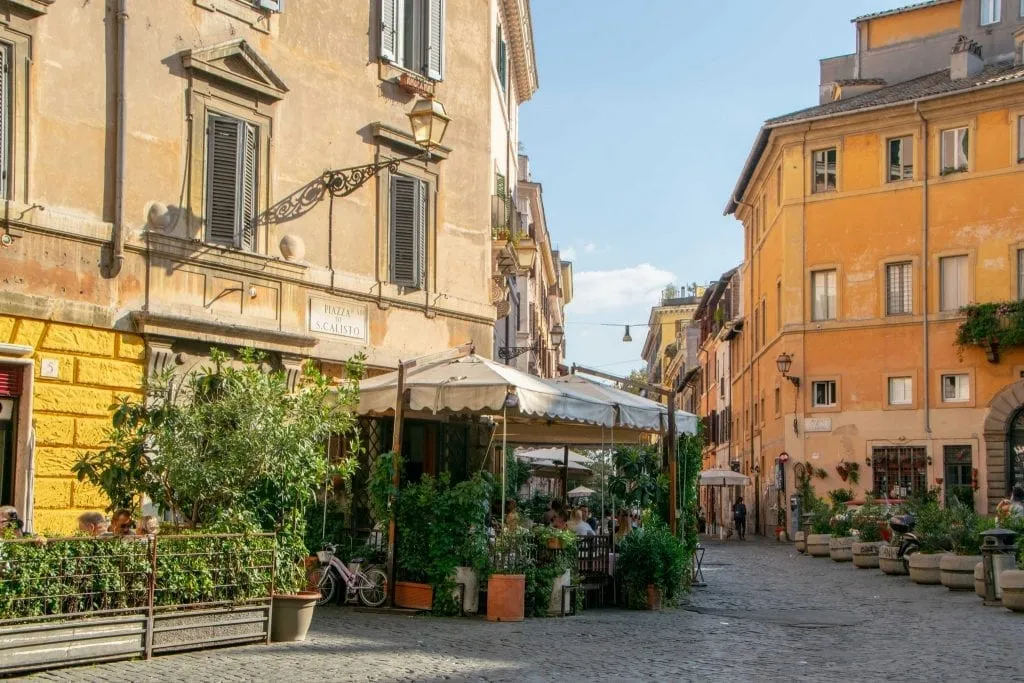 quiet street in trastevere rome with cafes in the distance