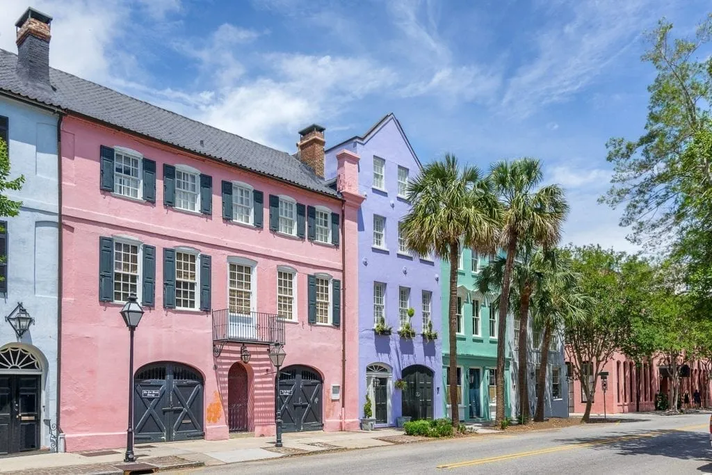 Rainbow Row in Charleston USA, a row of colorful houses. These are pink, purple, and green from left to right. Charleston is one of the best weekend trips for couples in USA!
