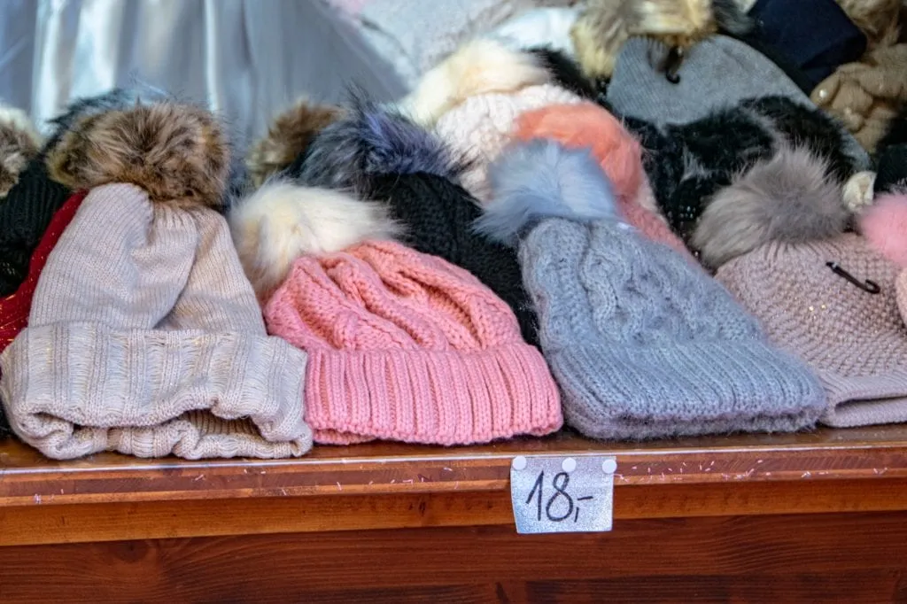 Pile of knit hats laying on a wooden table at a Christmas market in Innsbruck Austria--you'll be able to pick up plenty of souvenirs like this, so don't put too many accessories on your packing list for Europe winter!