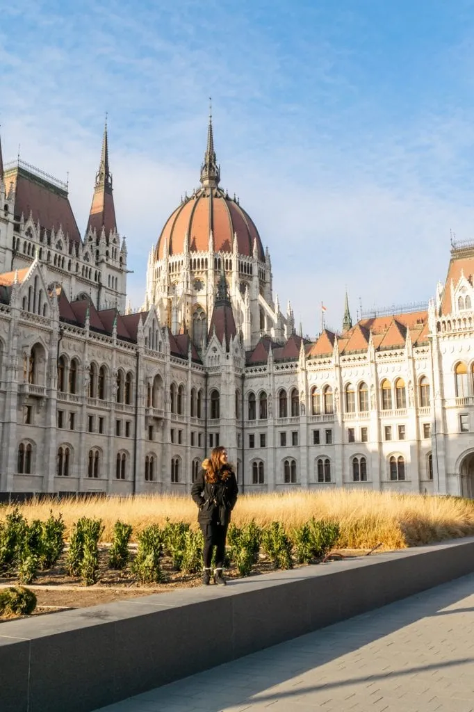 Woman in a black coat standing in front of Budapest Parliament in November.