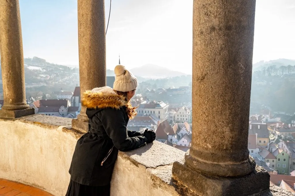 kate storm in a black coat at the top of castle tower czech republic