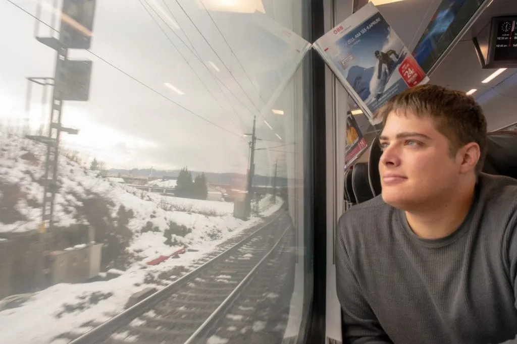 jeremy storm looking at a snowy landscape out the window on a train vienna to cesky krumlov