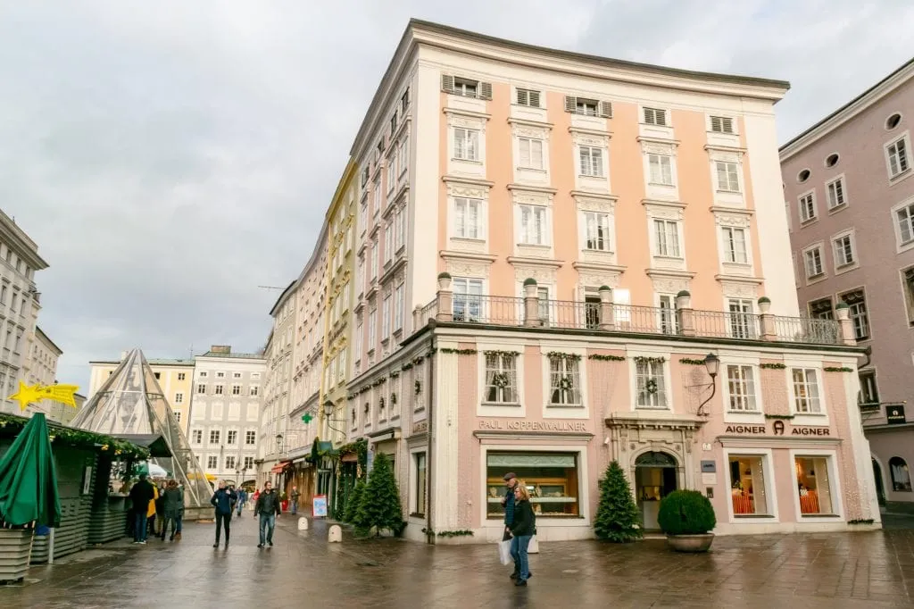 pink building in salzburg austria on a cloudy day with christmas market to the left