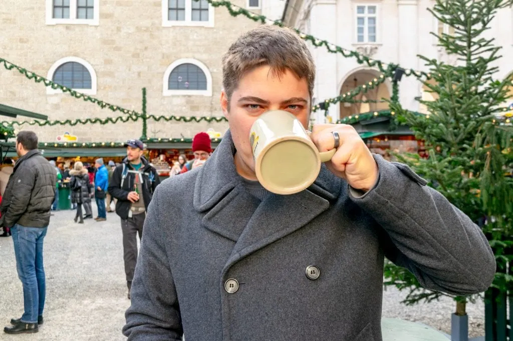jeremy drinking out of a large mug at a salzburg christmas market when visiting europe at christmas itinerary