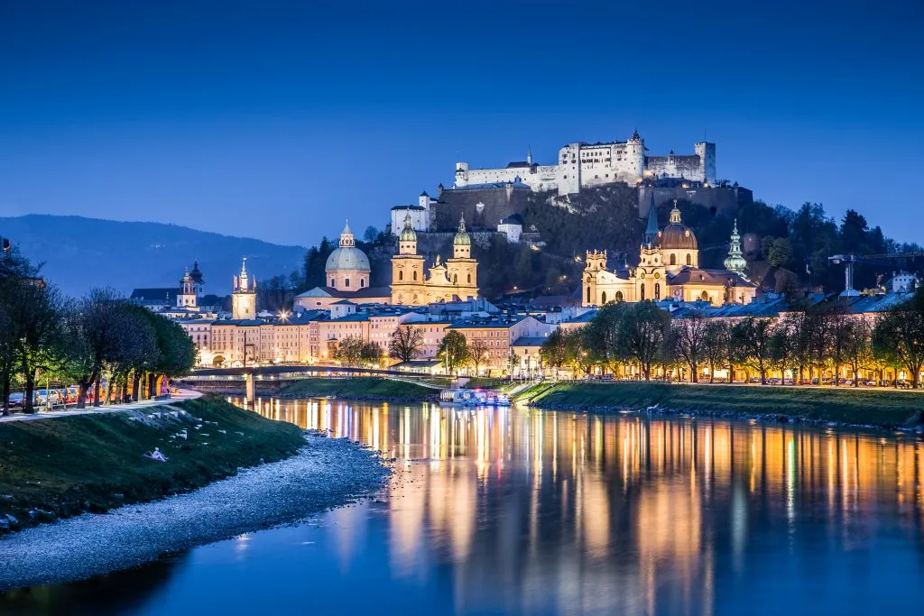 view of salzburg fortress at blue hour with the river in the foreground