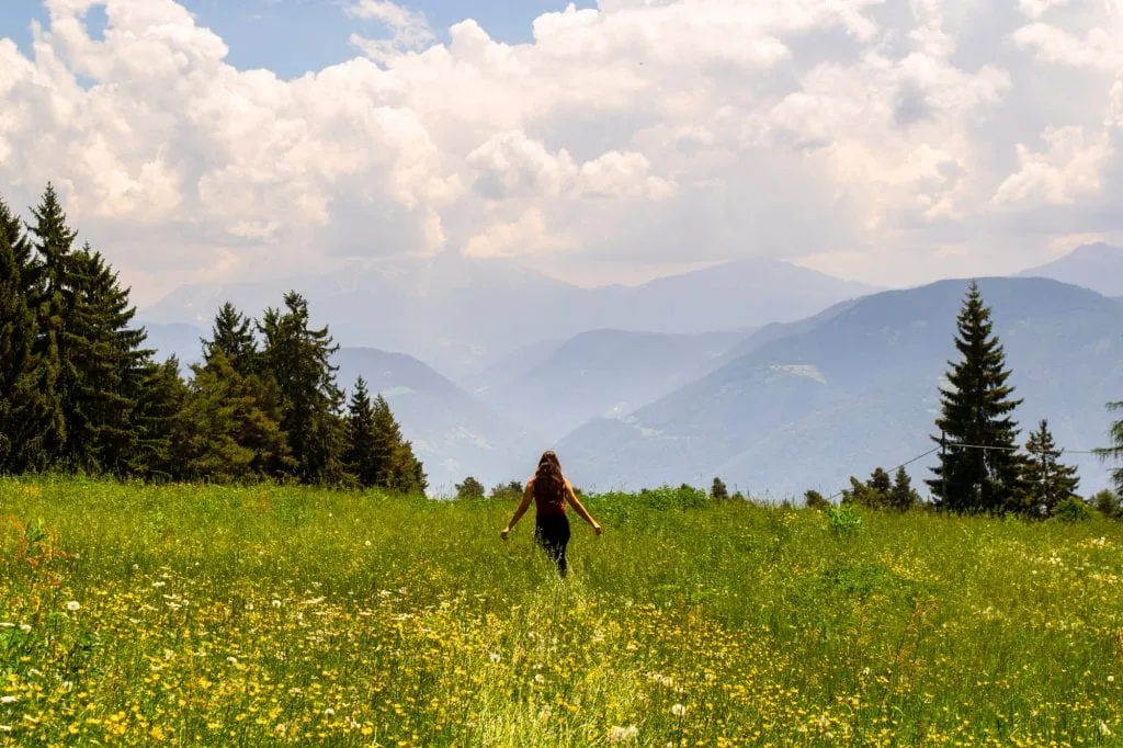 kate storm in a field of yellow flowers hiking in the dolomites, one of the best things to do in bolzano italy