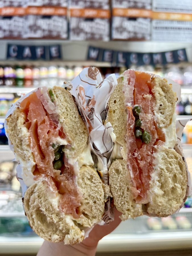 bagel of zuckers being held open to show salmon and cream cheese filling